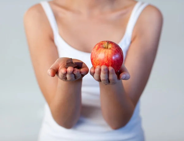 Woman showing chocolate and apple focus on chocolate — Stock Photo, Image