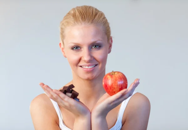 Friendly woman holding chocolate and apple focus on woman — Stock Photo, Image