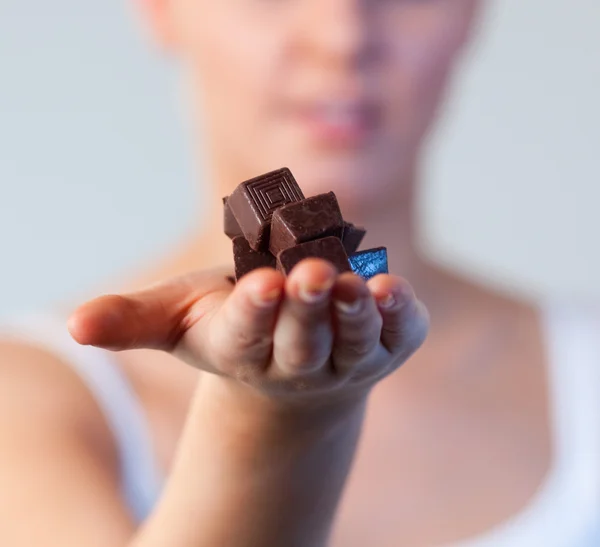 Close-up of an attractive woman holding chocolate focus on chocolate — Stock Photo, Image