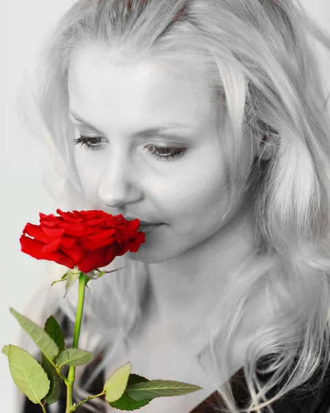 Beautiful woman in black and white smelling a red rose — Stock Photo, Image