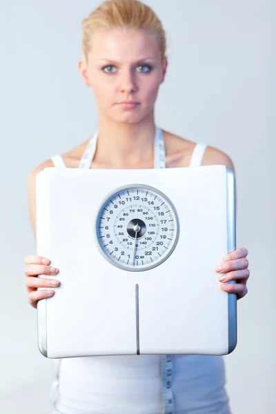 Серьёзная женщина держит весы с акцентом на весах — стоковое фото