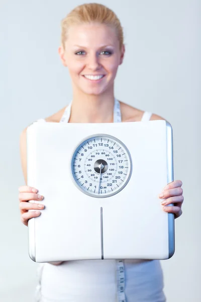 Mulher sorridente segurando uma balança com foco em escalas — Fotografia de Stock