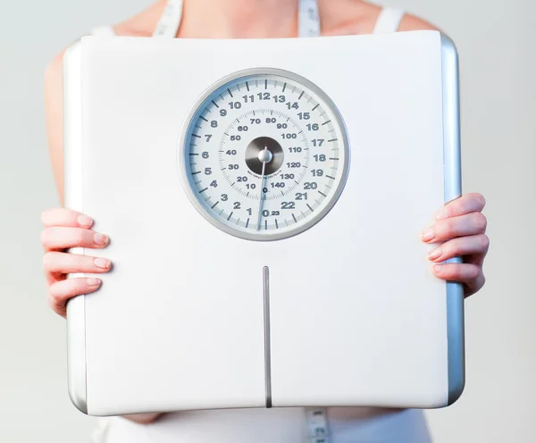 Крупним планом жінка тримає ваги з акцентом на ваги — стокове фото