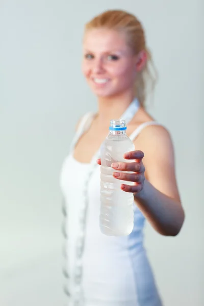Happy woman holding a bottle of water with focus on water — Stock Photo, Image