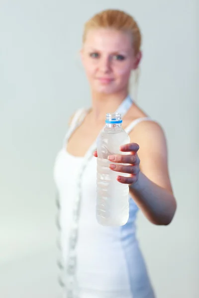 Friendly woman holding a bottle of water with focus on water — Stock Photo, Image
