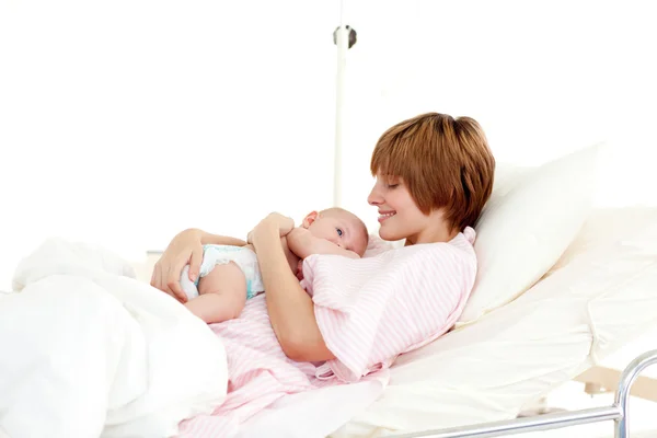微笑与新生的婴儿躺在床上的病人 — 图库照片