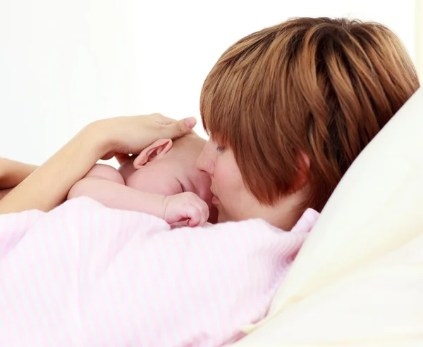 Retrato de una paciente besando a su bebé recién nacido en la cama — Foto de Stock