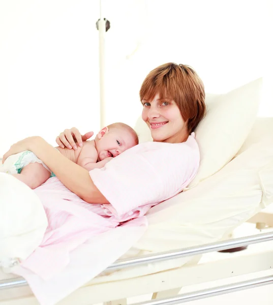 Yeni doğan bebek yatakta kameraya gülümseyen olan hasta — Stok fotoğraf