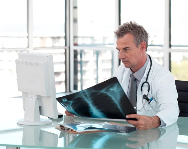 Äldre manliga läkare undersöka en röntgen — Stockfoto