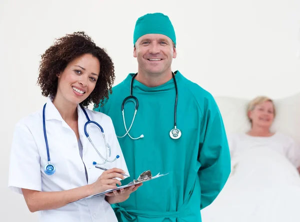 Retrato de médicos sorridentes examinando um paciente — Fotografia de Stock