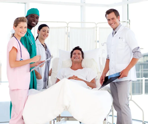 Ärzte, die einen Patienten betreuen, lächeln in die Kamera — Stockfoto