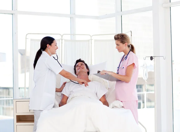 Female doctor and nurse looking after a patient — Stock Photo, Image