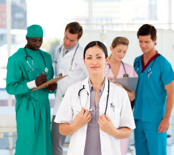 Vackra läkare med sitt team i bakgrunden — Stockfoto