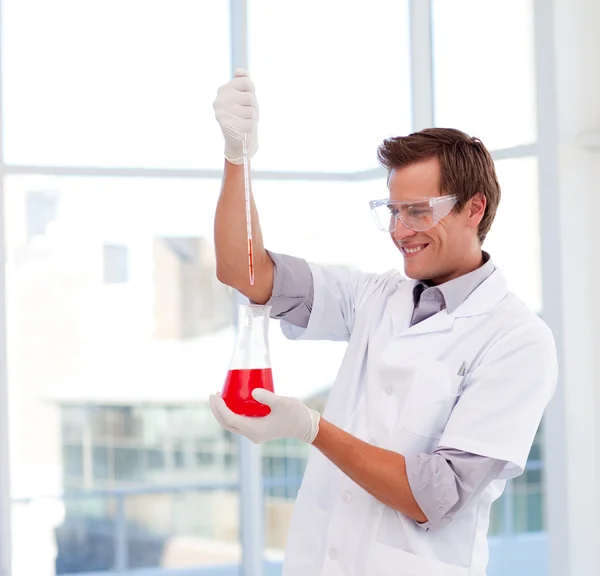 Lächelnder Wissenschaftler bei der Untersuchung eines Reagenzglases — Stockfoto