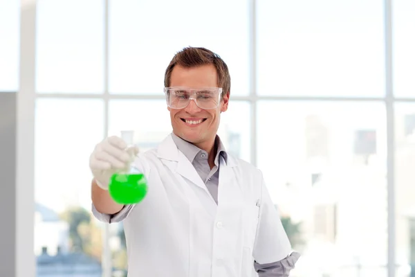 Улыбающийся ученый изучает химическую пробирку — стоковое фото