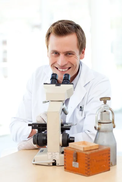 Scientifique souriant regardant à travers un microscope — Photo