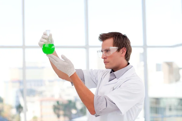 Científico sonriente examinando un tubo de ensayo químico — Foto de Stock