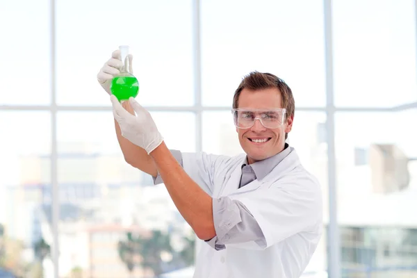 Cientista sorridente examinando um tubo de ensaio químico — Fotografia de Stock