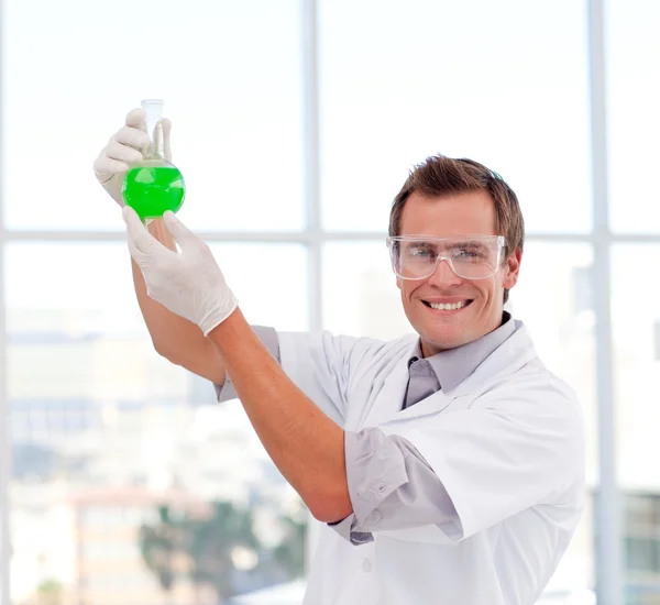 Scientist examining a test-tube smiling at the camera — Stock Photo, Image