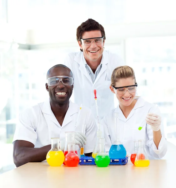 Scientists examining test-tubes smiling at the camera — Stock Photo, Image