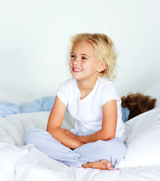 Kleines Mädchen sitzt vor dem Schlafen auf dem Bett — Stockfoto