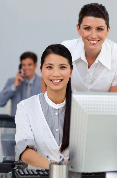 Mulher de negócios encantadora ajudando seu colega em um computador — Fotografia de Stock