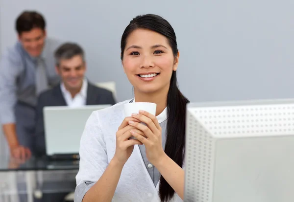 Charmante Aziatische zakenvrouw drinken een kopje koffie op haar Bureau — Stockfoto