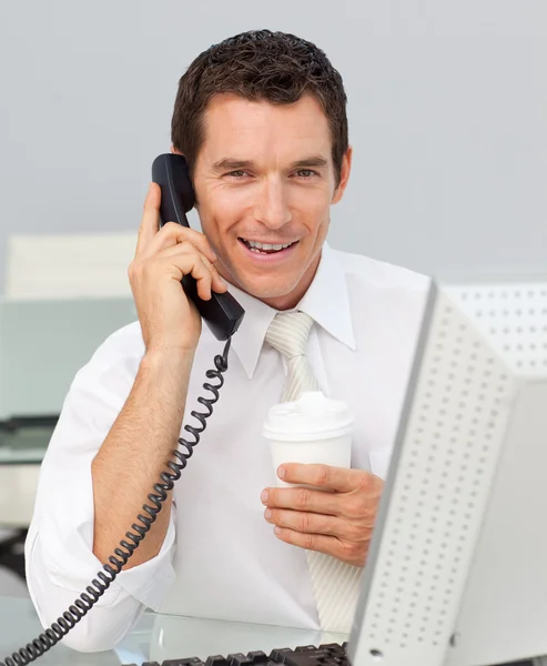 Χαμογελώντας επιχειρηματίας στο τηλέφωνο, πίνοντας ένα καφέ στο γραφείο — Φωτογραφία Αρχείου