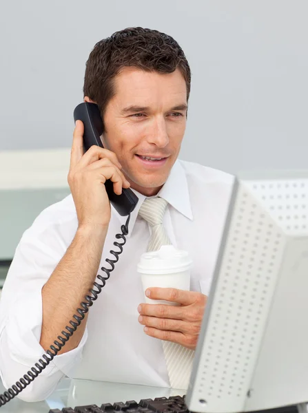 Привлекательный бизнесмен по телефону пьет кофе в офисе — стоковое фото