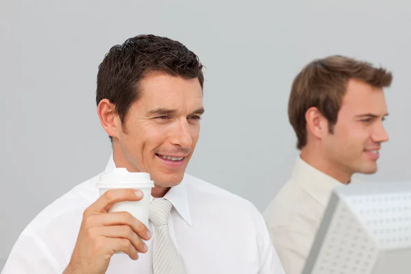 Businessman drinking coffee in the office while he is using the — Stock Photo, Image