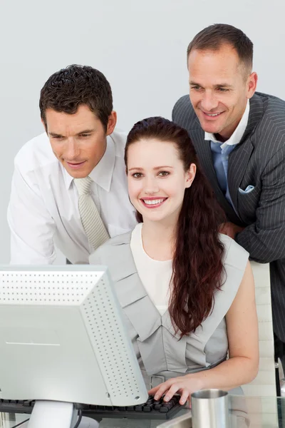 Empresária sorridente e dois empresários usando um computador — Fotografia de Stock