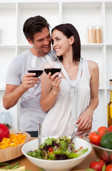 Lachende liefhebbers drinken van wijn en het voorbereiden van een salade — Stockfoto