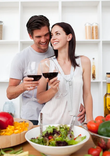 Smiling couple drinking wine and preparing a salad — Stock Photo, Image