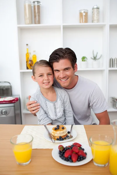 Батько їсть млинці з дочкою на кухні — стокове фото
