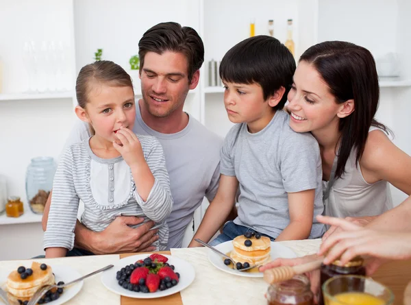 Familia sonriente comiendo panqueques para el desayuno — Foto de Stock