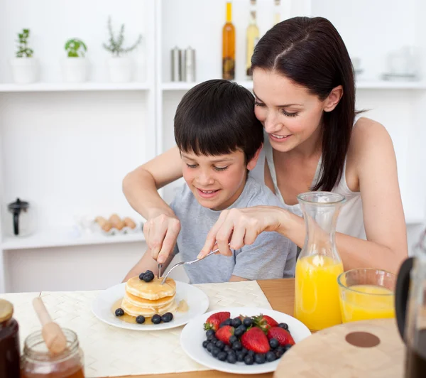 Retrato de uma mãe e seu filho comendo panquecas no café da manhã — Fotografia de Stock
