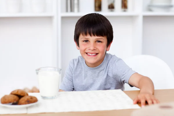 Usmíval se chlapec jíst sušenky a konzumní mléko — Stock fotografie