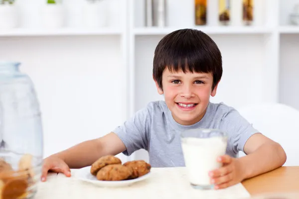 Happy boy eating biscuits and drinking milk — Stock Photo, Image