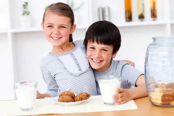 Portrait of happy brother and sister eating biscuits — Stock Photo, Image