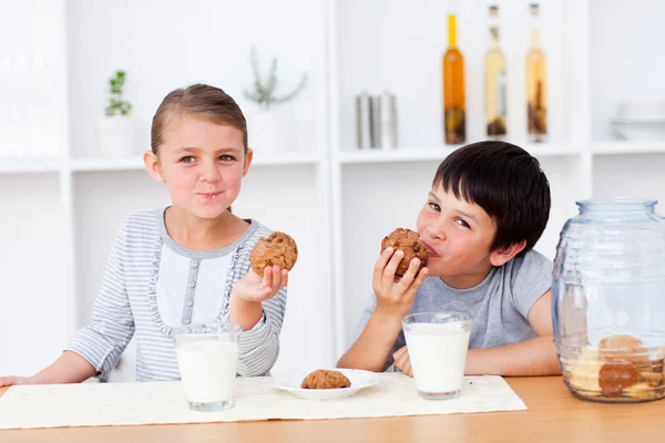 Siblings eating cookies and drinking milk — Stock Photo, Image