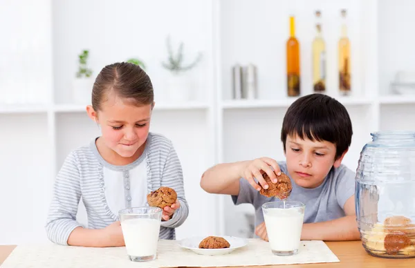 Hermano y hermana comiendo galletas y bebiendo leche — Foto de Stock