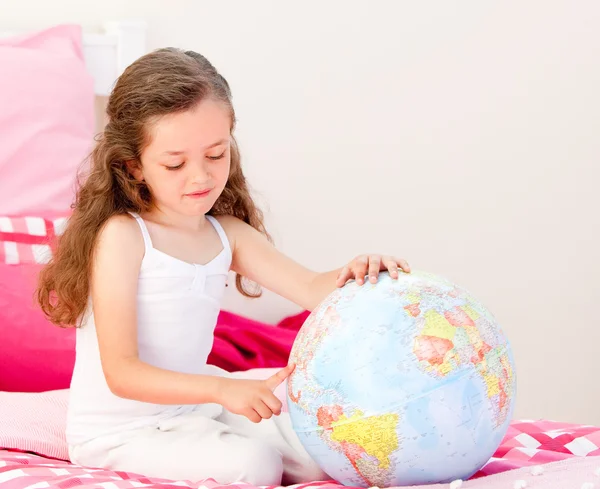 Bedårande liten flicka som håller en terrestrial globe sitter på henne — Stockfoto