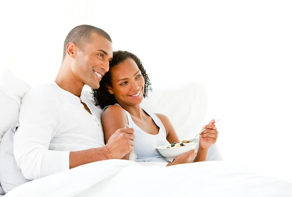 Loving couple having breakfast lying on their bed — Stock Photo, Image