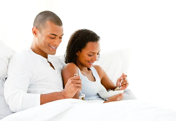 Smiling couple having breakfast lying on their bed — Stock Photo, Image