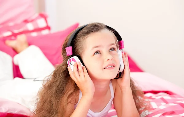 Onu yatakta yatarken şirin küçük kız müzik dinleme — Stok fotoğraf