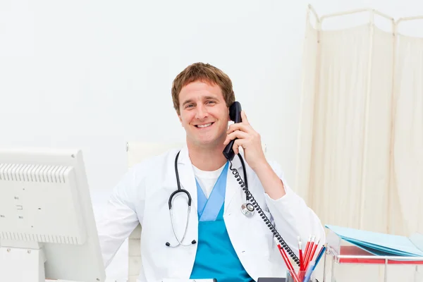 Un médecin au téléphone souriant à la caméra — Photo