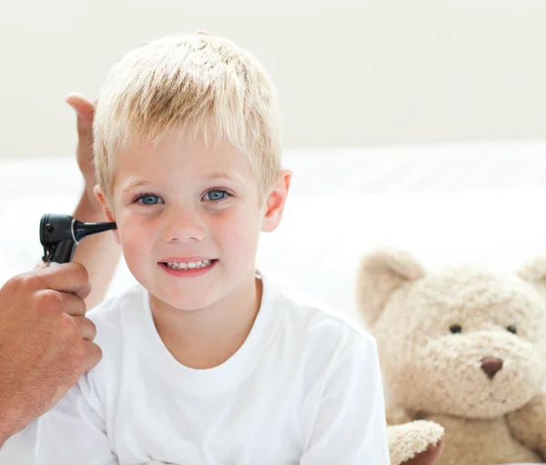 Een arts onderzoekt een lachende jongetje oren — Stockfoto