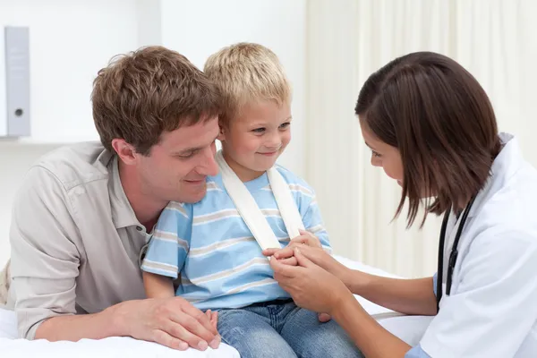 Улыбающийся доктор осматривает руку маленького мальчика — стоковое фото