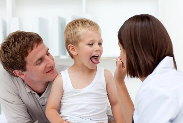 Doctor examining a little boy with his father in tow — Stock Photo, Image