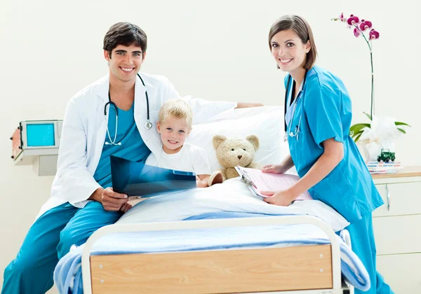 En läkare och en sjuksköterska som visar en röntgen till en liten pojke — Stockfoto